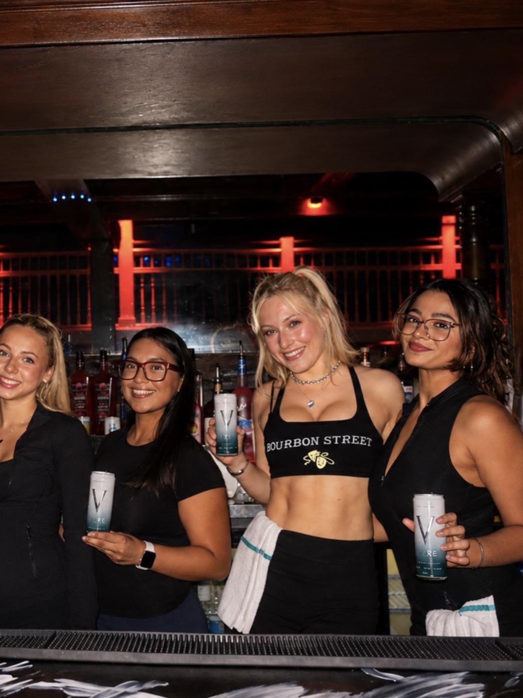 Bartenders holding VYRE cans behind the bar